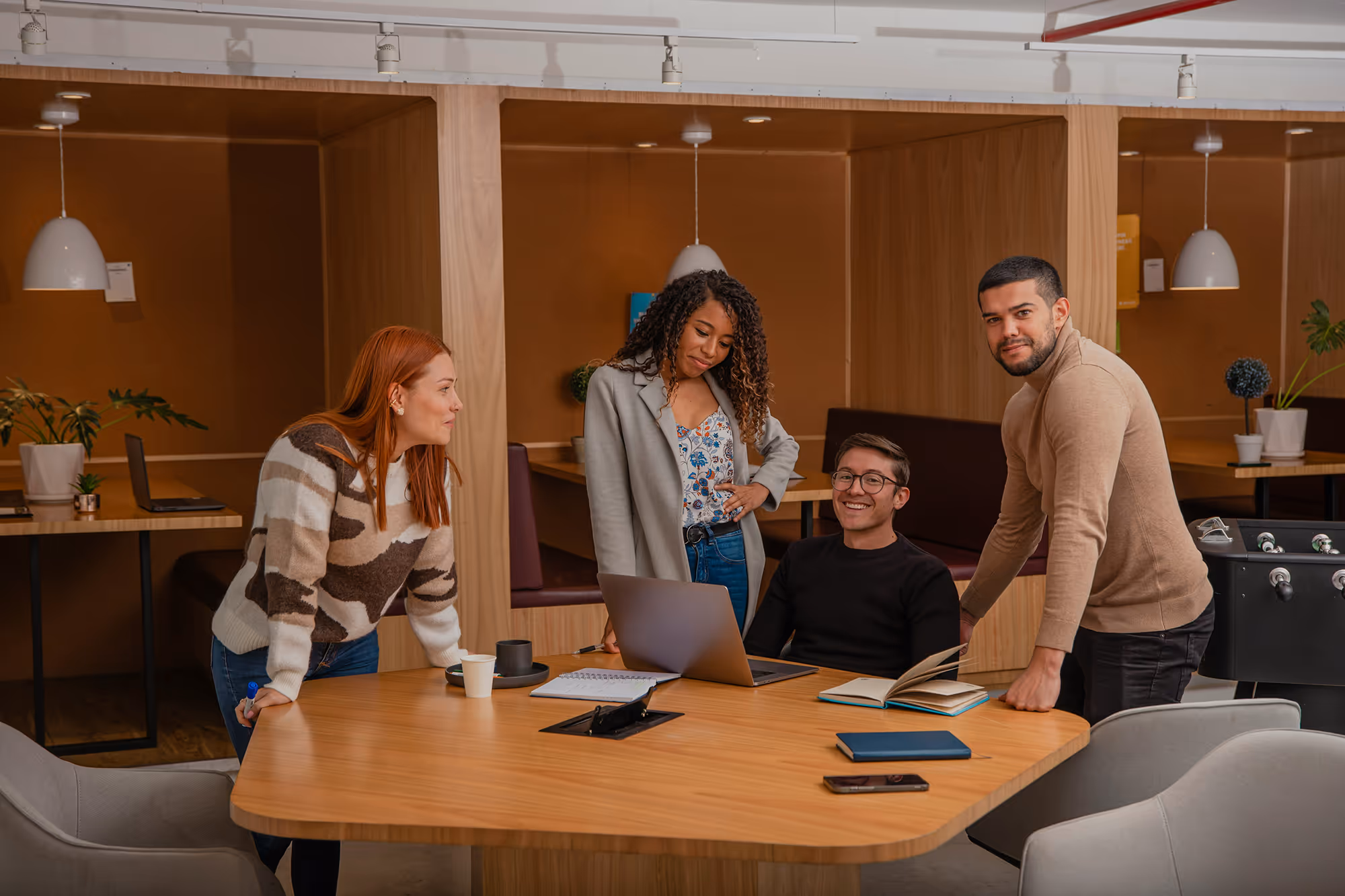 A group of people working around a desk smiling.
